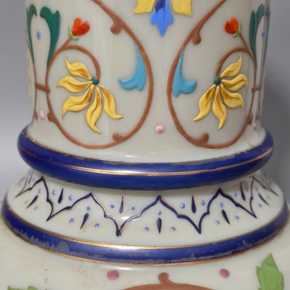 An antique cream opaque glass vase featuring hand-painted floral arabesque enamel patterns in bright colours with gilded accents and cobalt blue bands. View X