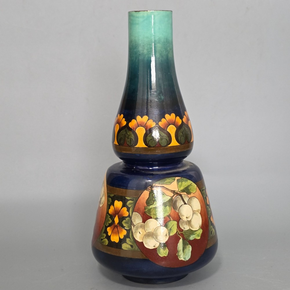 A late Victorian double-gourd earthenware vase with hand-painted fruit roundels, stylized floral bands, and a gradient turquoise to blue neck.