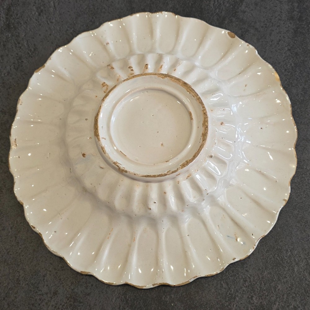 A 17th-century Dutch Delftware lobed ceramic dish hand-painted with a blue, yellow, and green floral border and a central figure. View IX