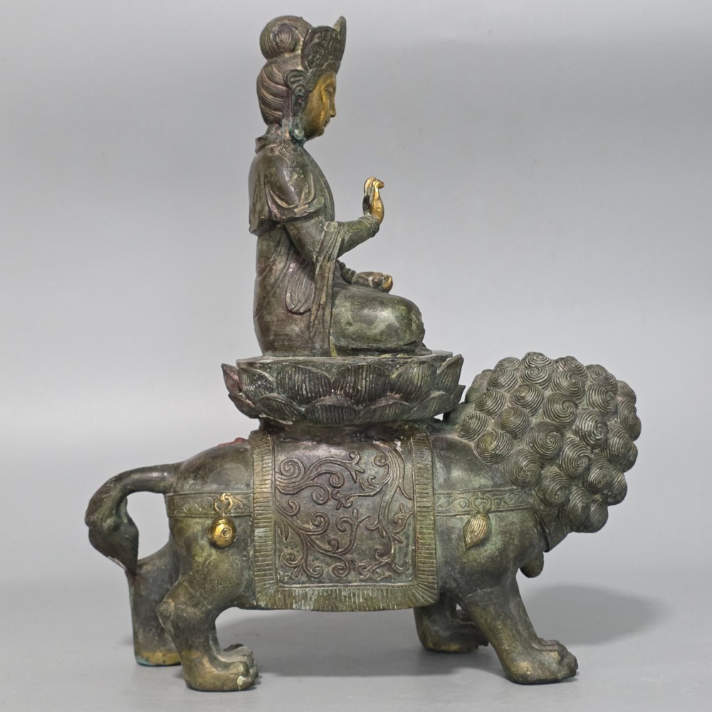 A 19th-century cast bronze sculpture depicting a seated Guanyin figure with gilded facial details riding atop a textured Dog of Fo. View IV