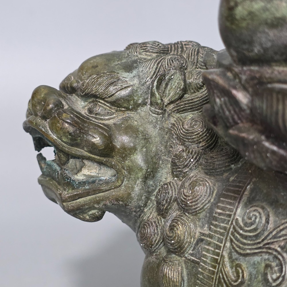 A 19th-century cast bronze sculpture depicting a seated Guanyin figure with gilded facial details riding atop a textured Dog of Fo. View V