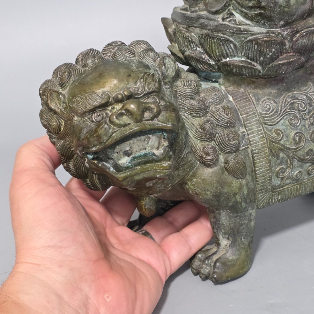 A 19th-century cast bronze sculpture depicting a seated Guanyin figure with gilded facial details riding atop a textured Dog of Fo. View II