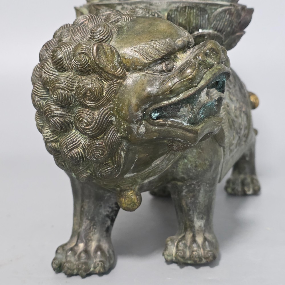 A 19th-century cast bronze sculpture depicting a seated Guanyin figure with gilded facial details riding atop a textured Dog of Fo. View VI