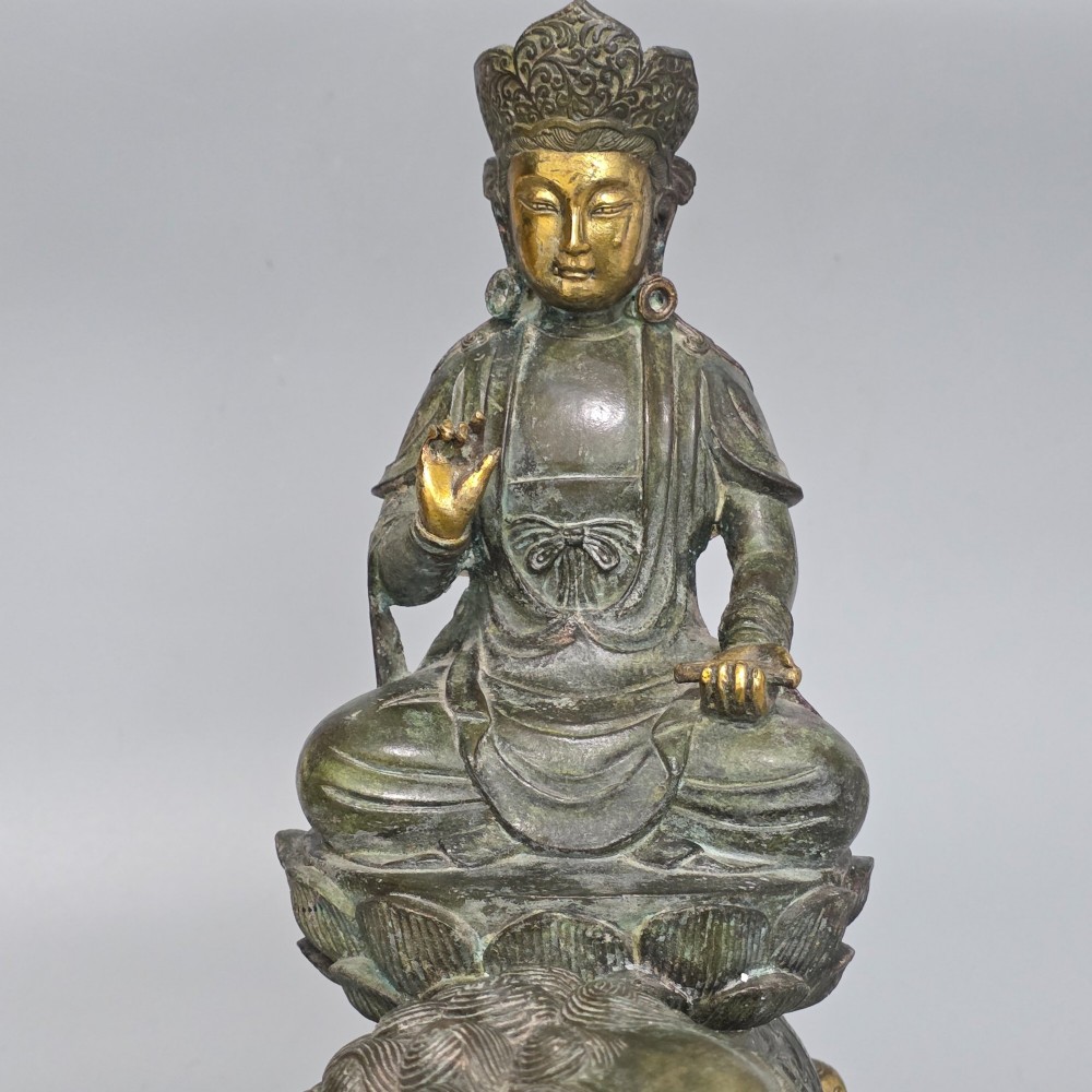 A 19th-century cast bronze sculpture depicting a seated Guanyin figure with gilded facial details riding atop a textured Dog of Fo. View VII