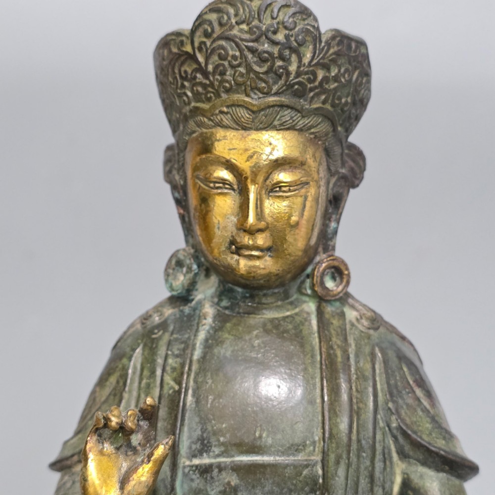 A 19th-century cast bronze sculpture depicting a seated Guanyin figure with gilded facial details riding atop a textured Dog of Fo. View VIII