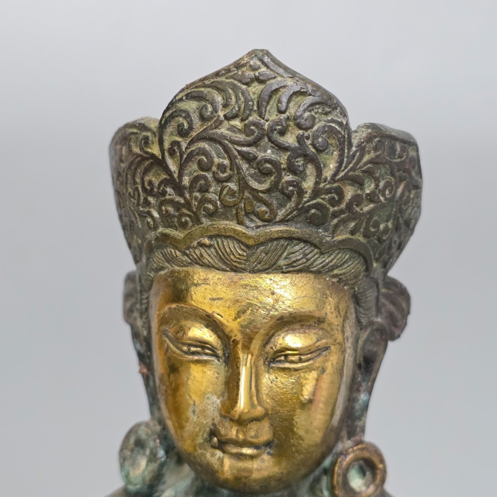 A 19th-century cast bronze sculpture depicting a seated Guanyin figure with gilded facial details riding atop a textured Dog of Fo. View IX