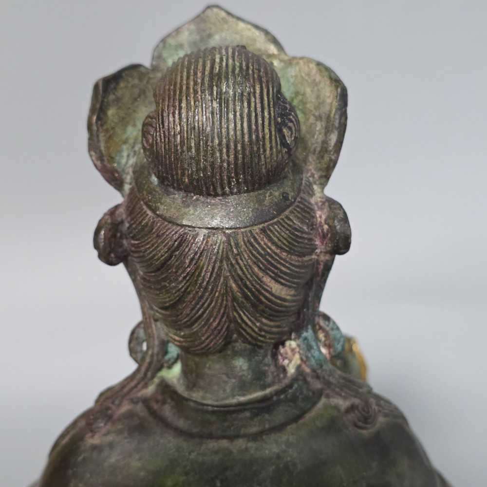 A 19th-century cast bronze sculpture depicting a seated Guanyin figure with gilded facial details riding atop a textured Dog of Fo. View X