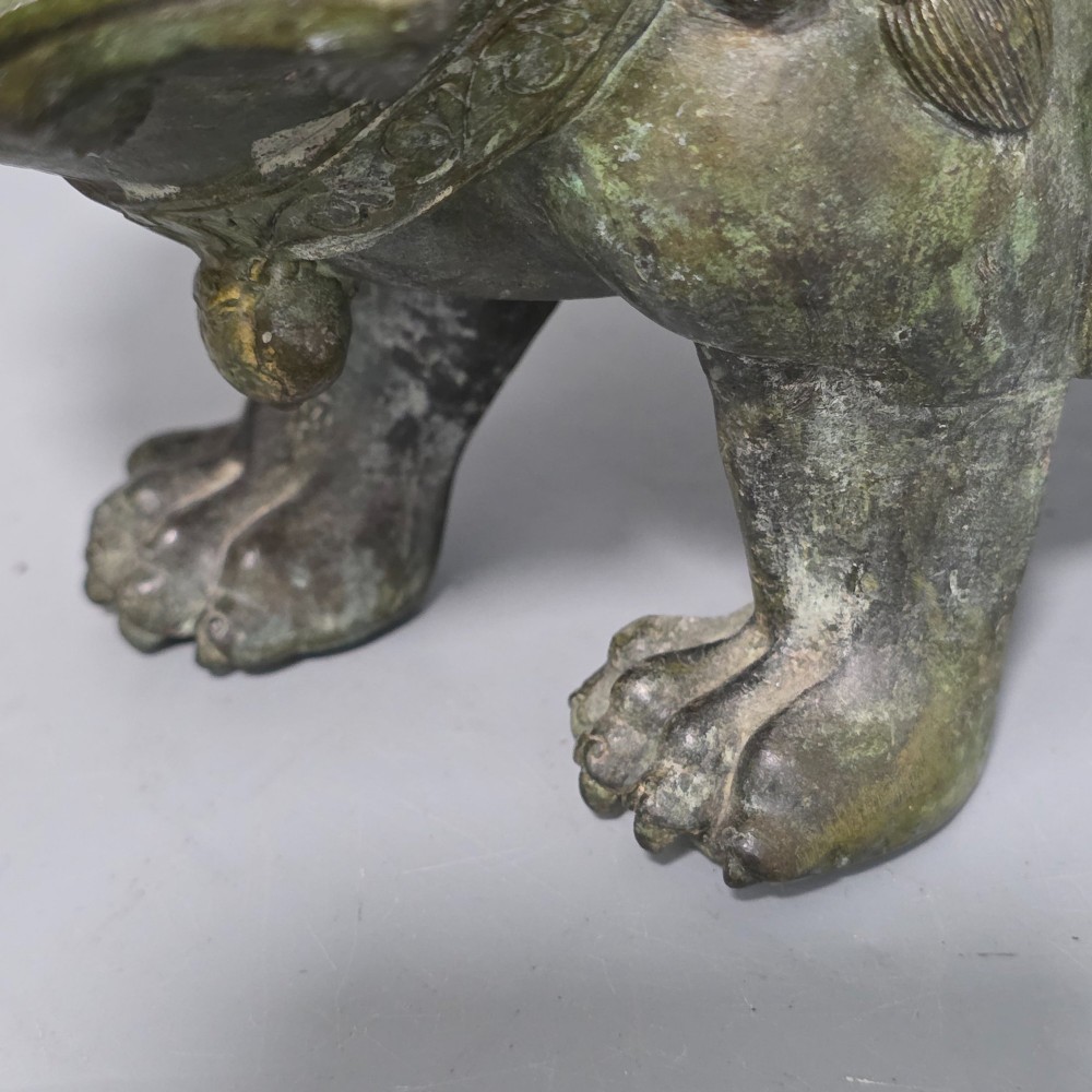 A 19th-century cast bronze sculpture depicting a seated Guanyin figure with gilded facial details riding atop a textured Dog of Fo. View XI