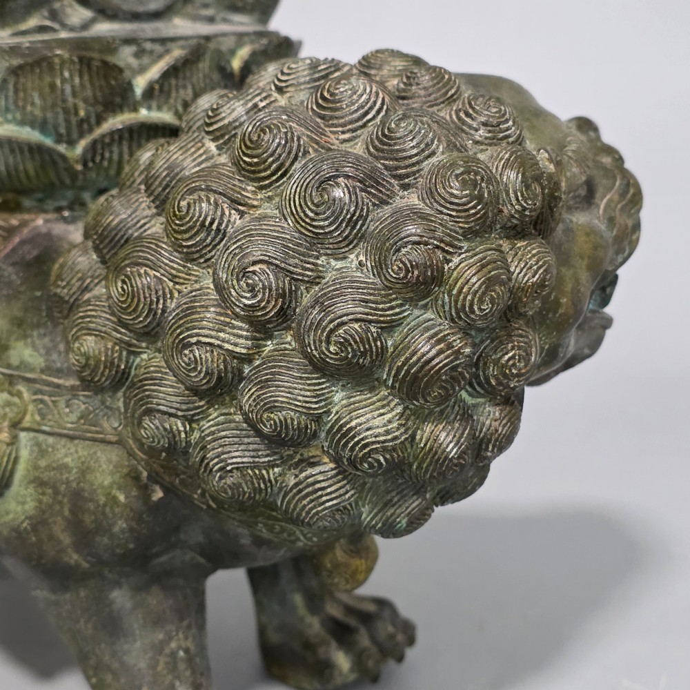 A 19th-century cast bronze sculpture depicting a seated Guanyin figure with gilded facial details riding atop a textured Dog of Fo. View XII
