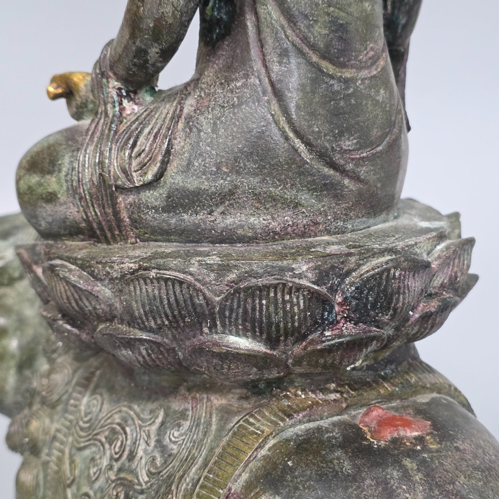 A 19th-century cast bronze sculpture depicting a seated Guanyin figure with gilded facial details riding atop a textured Dog of Fo. View XIV