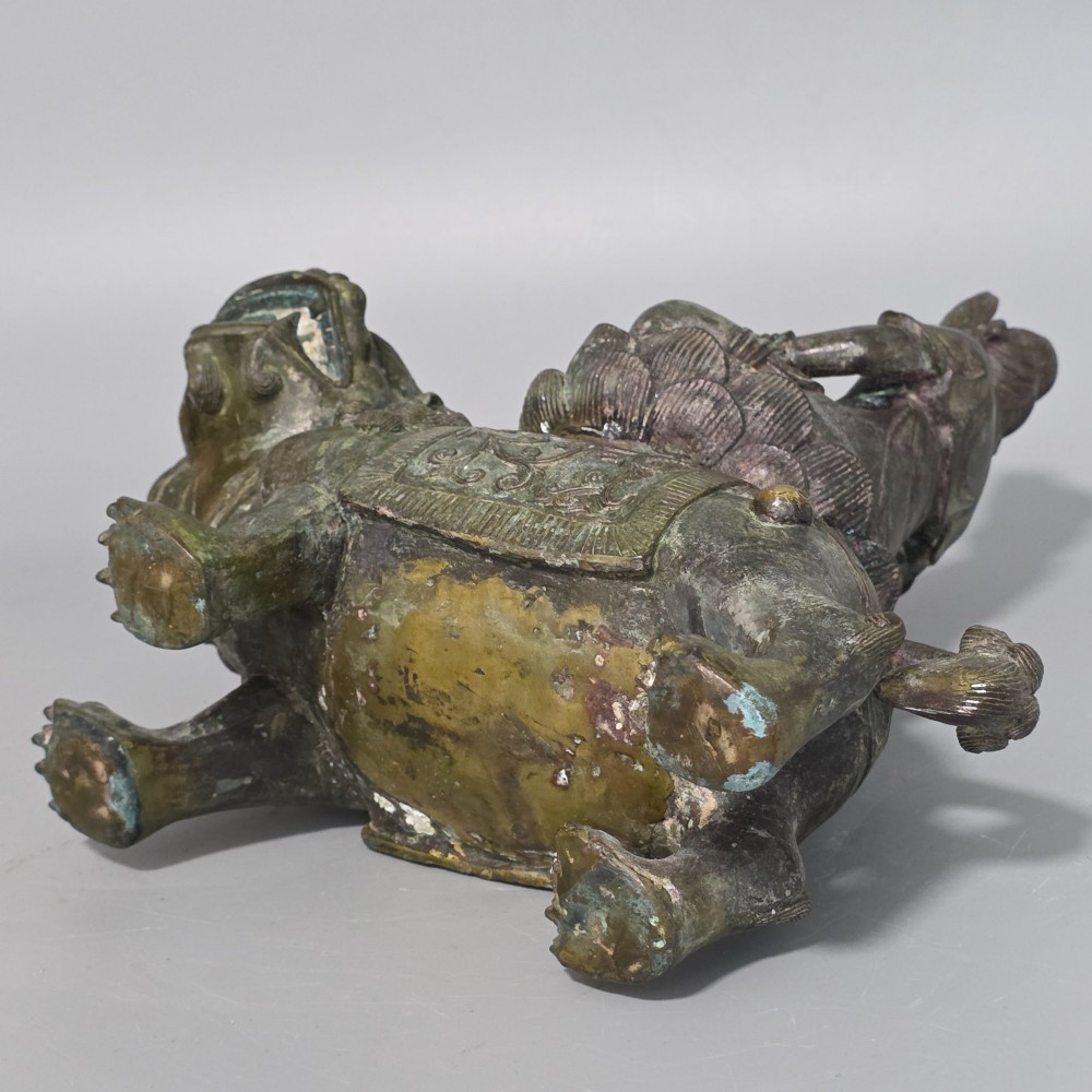 A 19th-century cast bronze sculpture depicting a seated Guanyin figure with gilded facial details riding atop a textured Dog of Fo. View XV