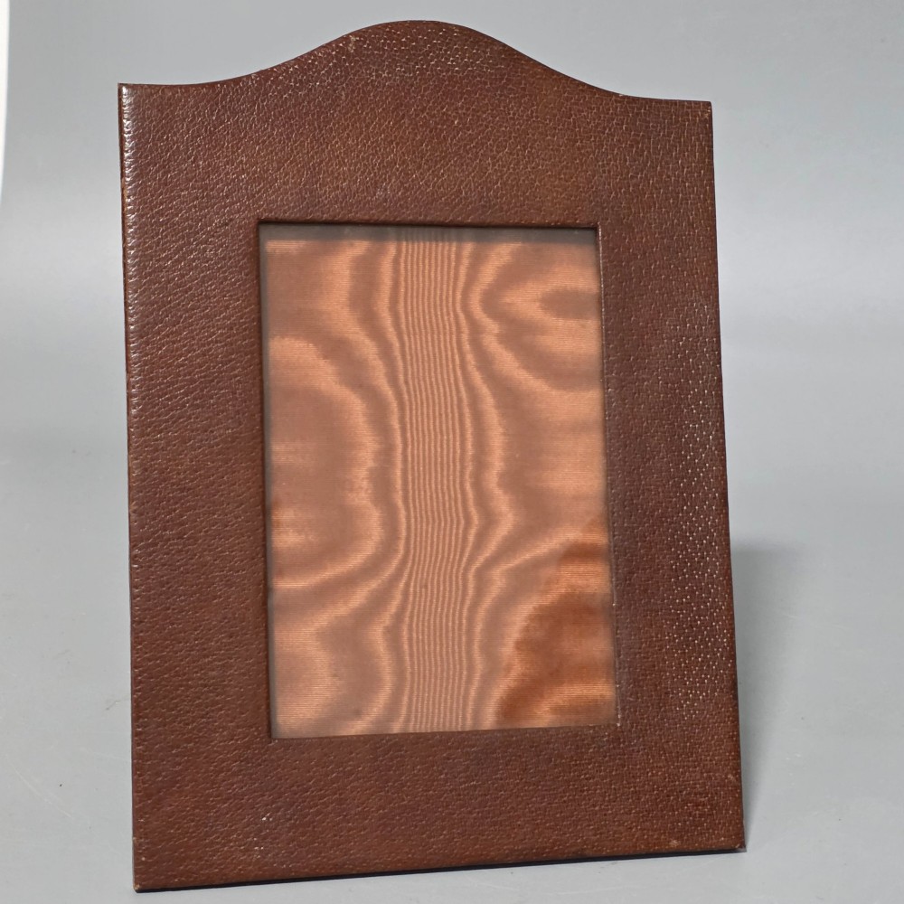 A brown textured leather photo frame featuring an arched top and a central rectangular aperture backed with moire silk. View VI