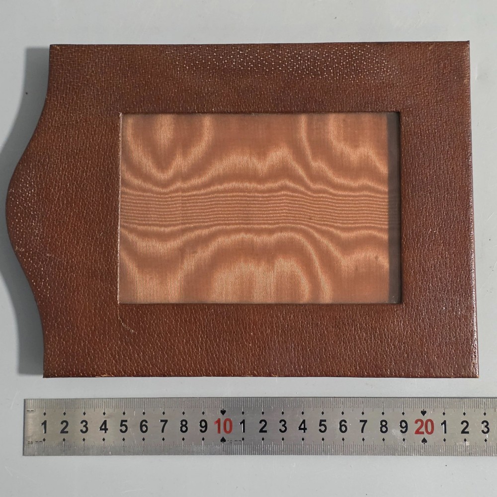 A brown textured leather photo frame featuring an arched top and a central rectangular aperture backed with moire silk. View IX