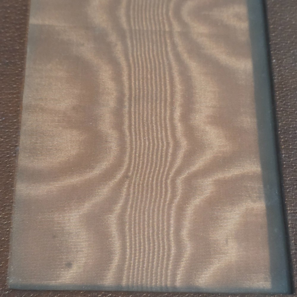 A brown textured leather photo frame featuring an arched top and a central rectangular aperture backed with moire silk. View X