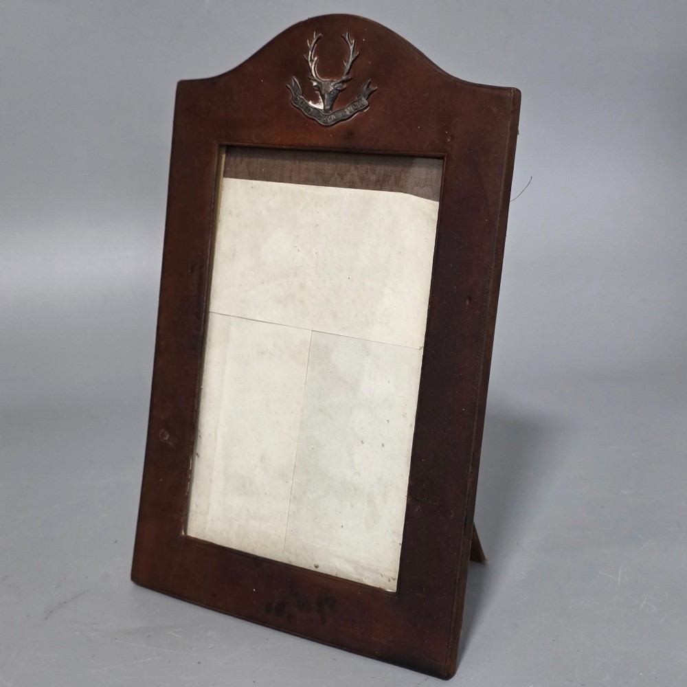 A dark brown leather desktop picture frame featuring an arched top decorated with a metal stag head emblem and motto scroll. View II