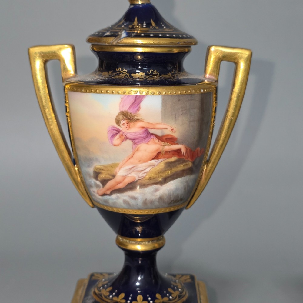 A pair of cobalt blue and gold Vienna porcelain Empire amphora vases featuring hand-painted classical figures and square plinth bases. View VI