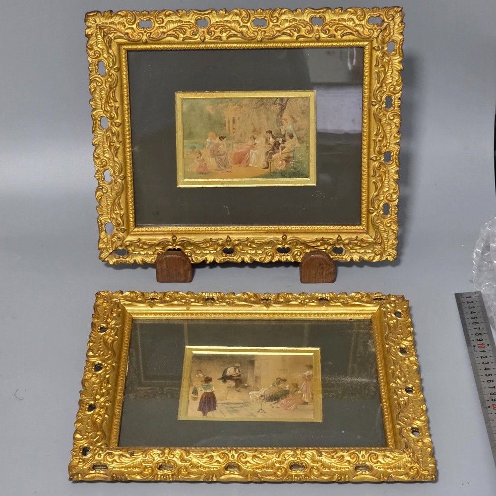 A pair of rectangular antique gilt-framed pictures featuring figurative genre scenes set against dark matting.