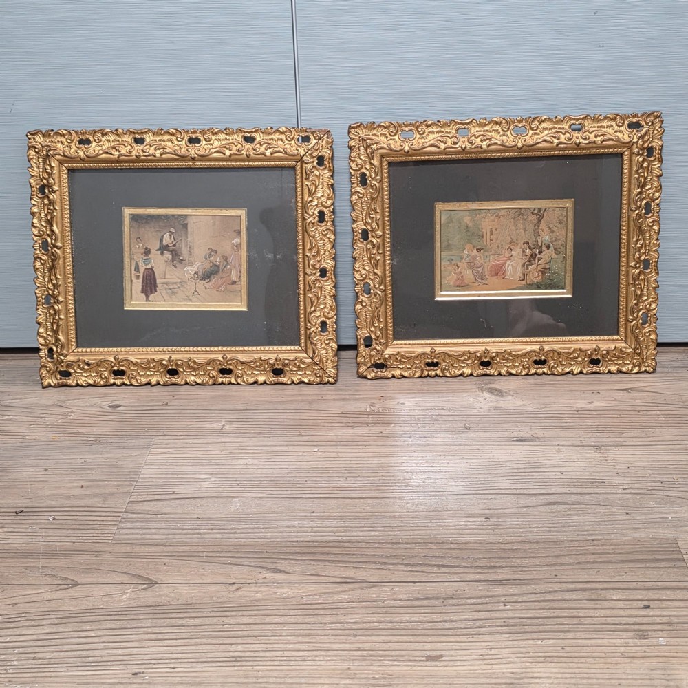 A pair of rectangular antique gilt-framed pictures featuring figurative genre scenes set against dark matting. View II