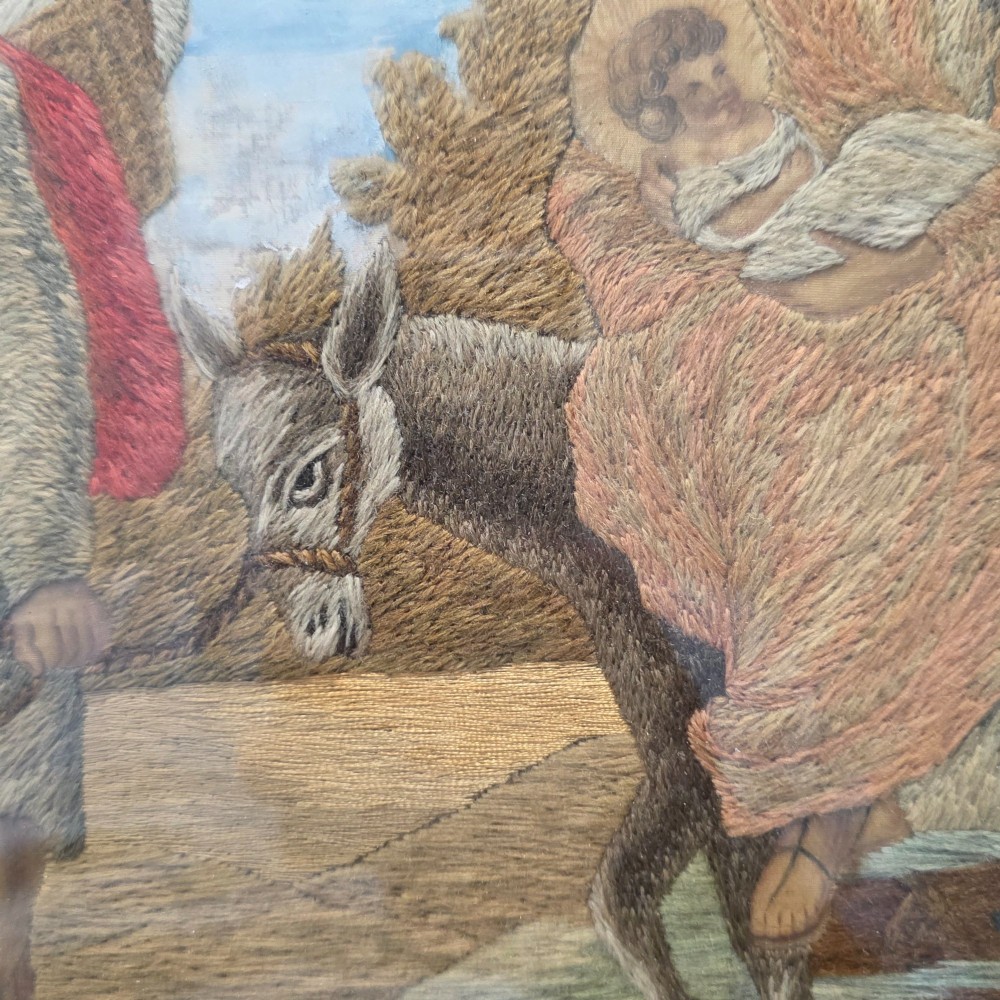 A framed Georgian silkwork and woolwork picture depicting the Flight into Egypt inside an oval glass reserve and a giltwood frame. View XIII