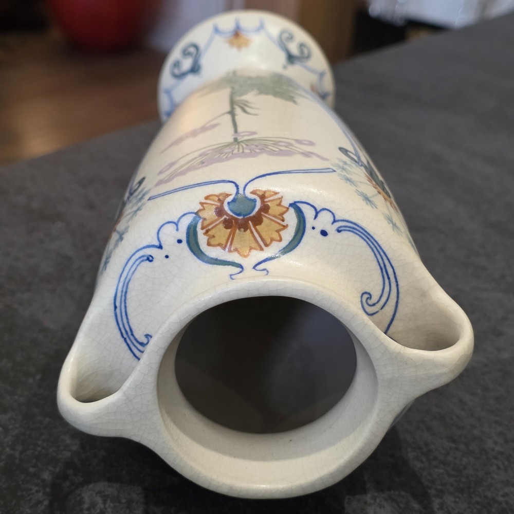 A pair of tall cream ceramic Art Nouveau vases featuring integral twin handles and hand-painted purple and green stylised floral motifs. View VI
