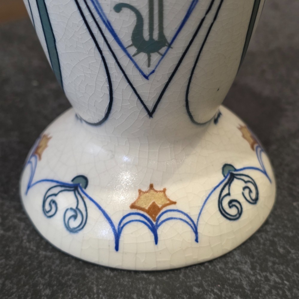 A pair of tall cream ceramic Art Nouveau vases featuring integral twin handles and hand-painted purple and green stylised floral motifs. View X