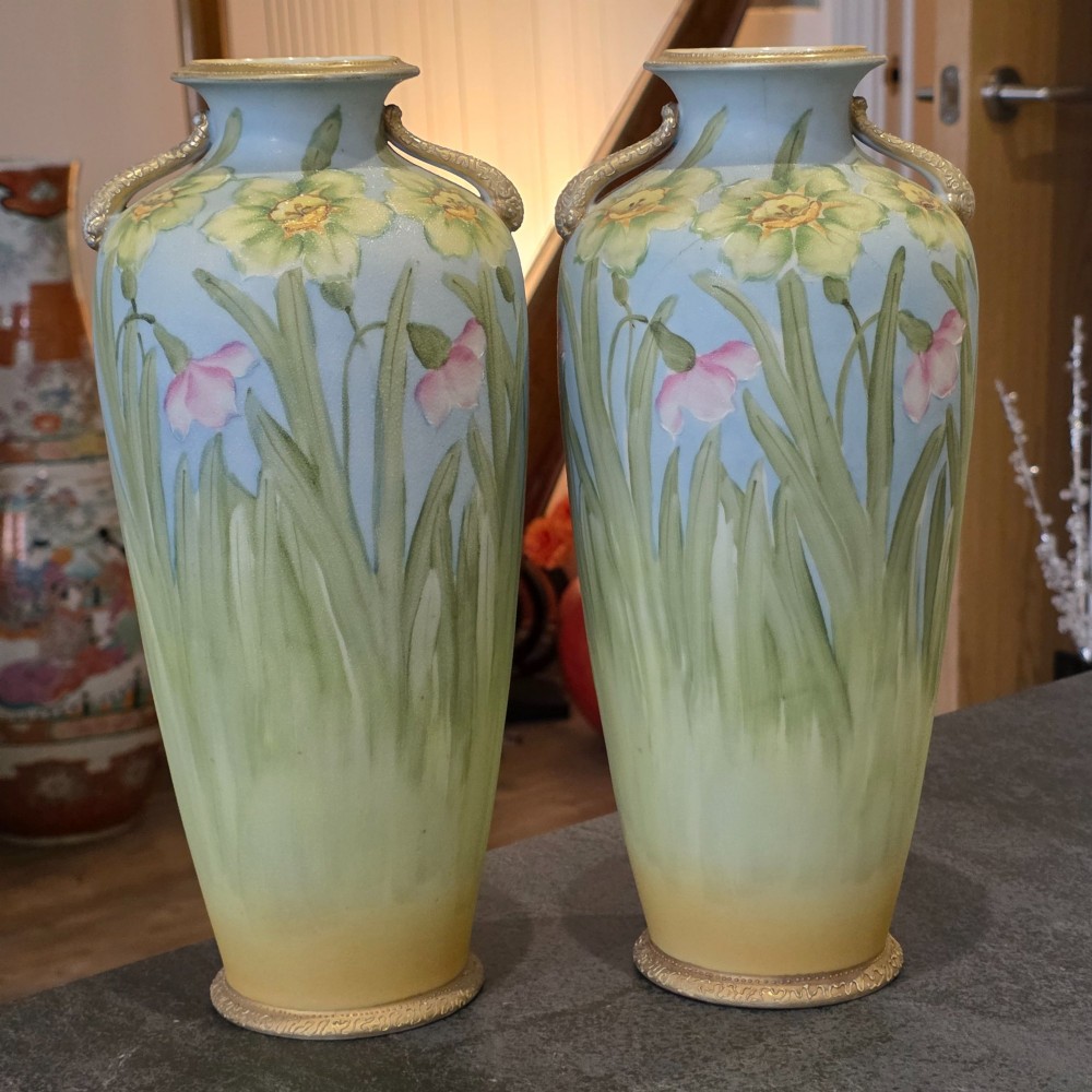 A pair of baluster-shaped porcelain vases featuring hand-painted daffodil and blossom motifs over a light blue and yellow gradient background with small gilded handles. View II