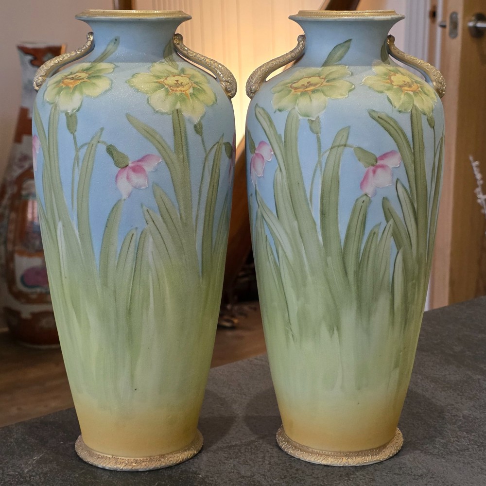 A pair of baluster-shaped porcelain vases featuring hand-painted daffodil and blossom motifs over a light blue and yellow gradient background with small gilded handles. View IV