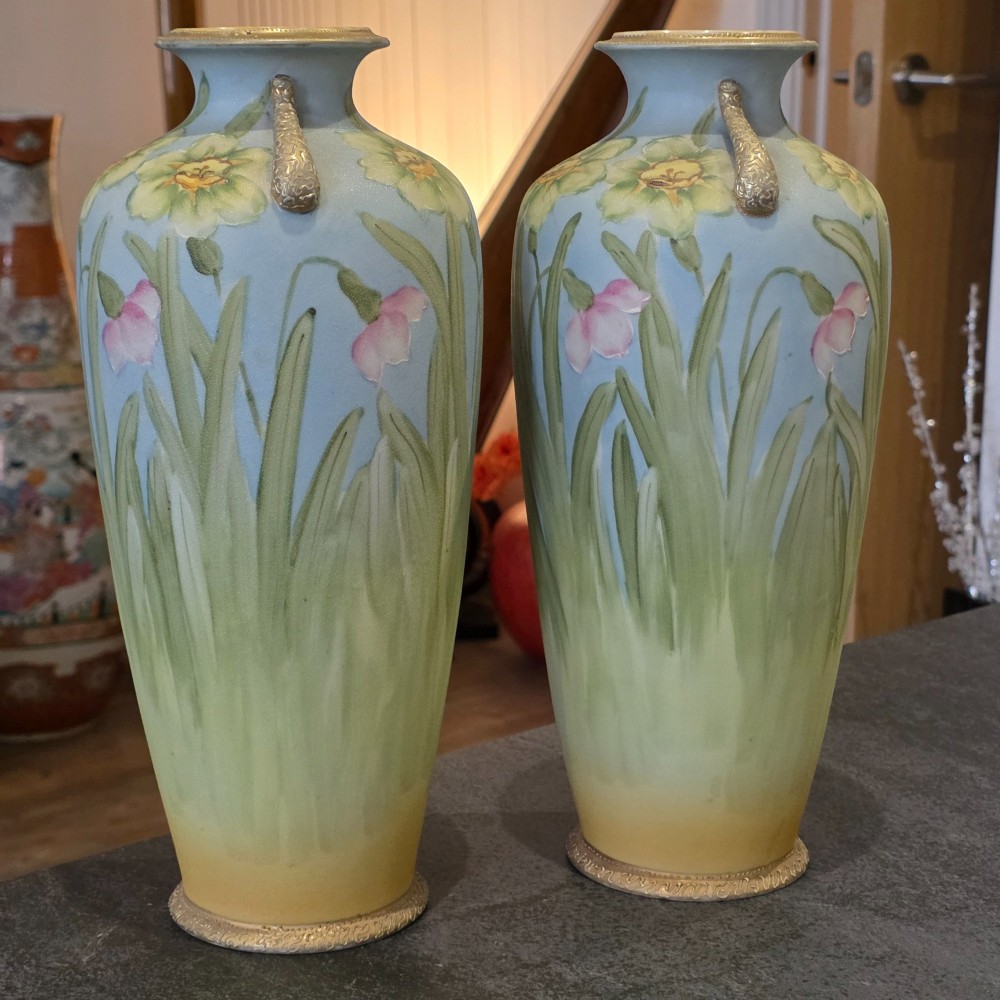 A pair of baluster-shaped porcelain vases featuring hand-painted daffodil and blossom motifs over a light blue and yellow gradient background with small gilded handles. View V