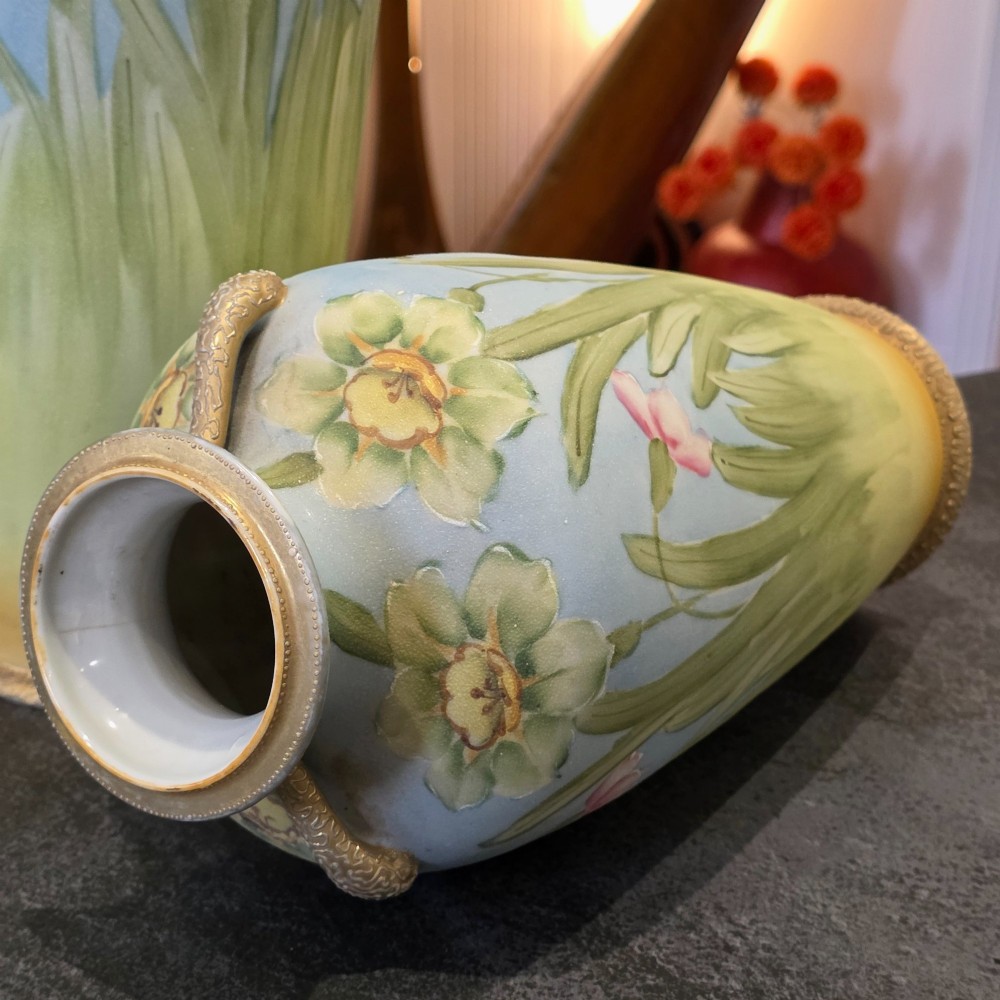 A pair of baluster-shaped porcelain vases featuring hand-painted daffodil and blossom motifs over a light blue and yellow gradient background with small gilded handles. View VI