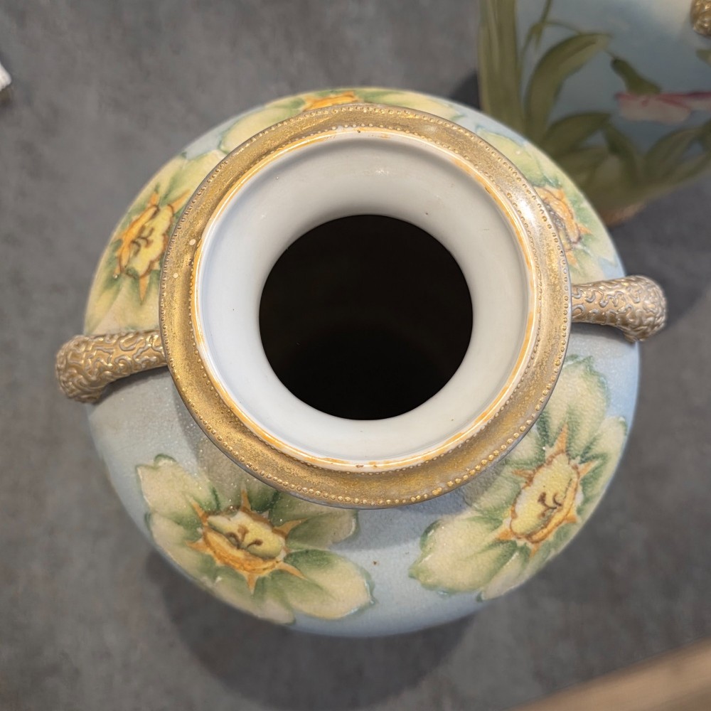 A pair of baluster-shaped porcelain vases featuring hand-painted daffodil and blossom motifs over a light blue and yellow gradient background with small gilded handles. View VII