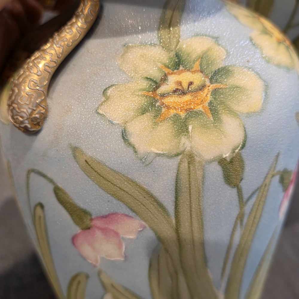 A pair of baluster-shaped porcelain vases featuring hand-painted daffodil and blossom motifs over a light blue and yellow gradient background with small gilded handles. View IX