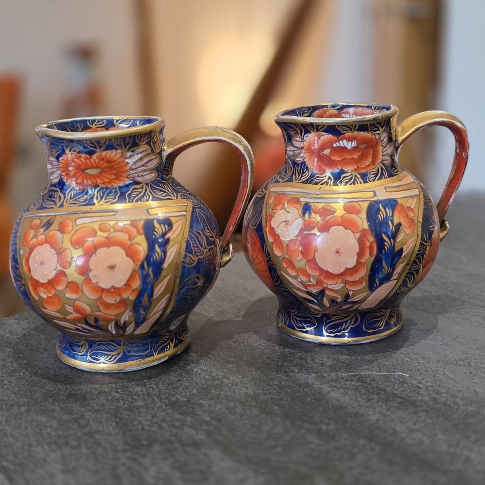 A pair of bulbous stoneware jugs decorated in cobalt blue, terracotta, and gold Imari style patterns with raised handles. View II