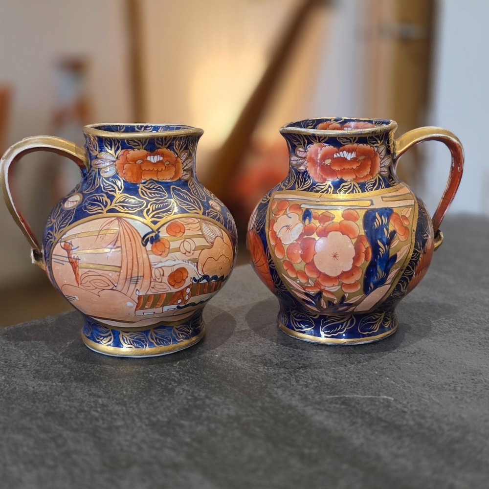 A pair of bulbous stoneware jugs decorated in cobalt blue, terracotta, and gold Imari style patterns with raised handles. View IV