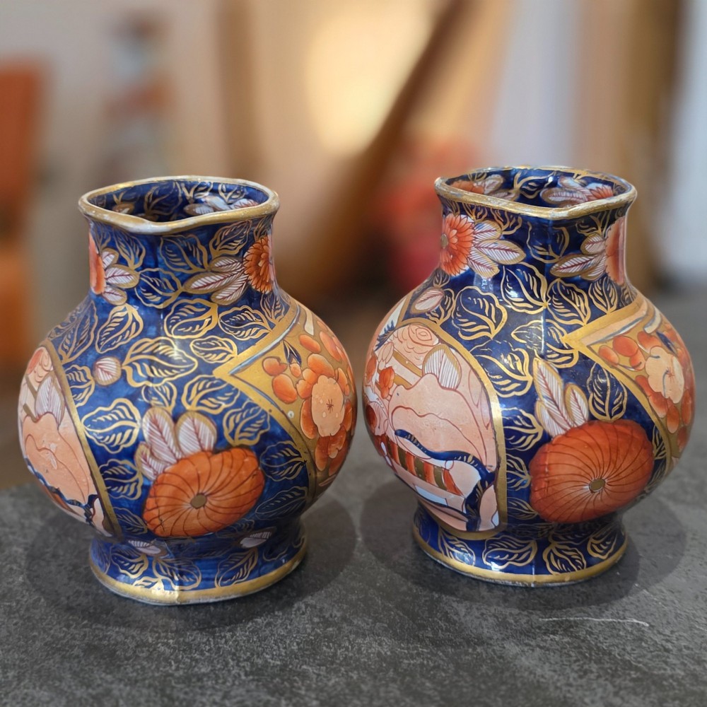 A pair of bulbous stoneware jugs decorated in cobalt blue, terracotta, and gold Imari style patterns with raised handles. View V