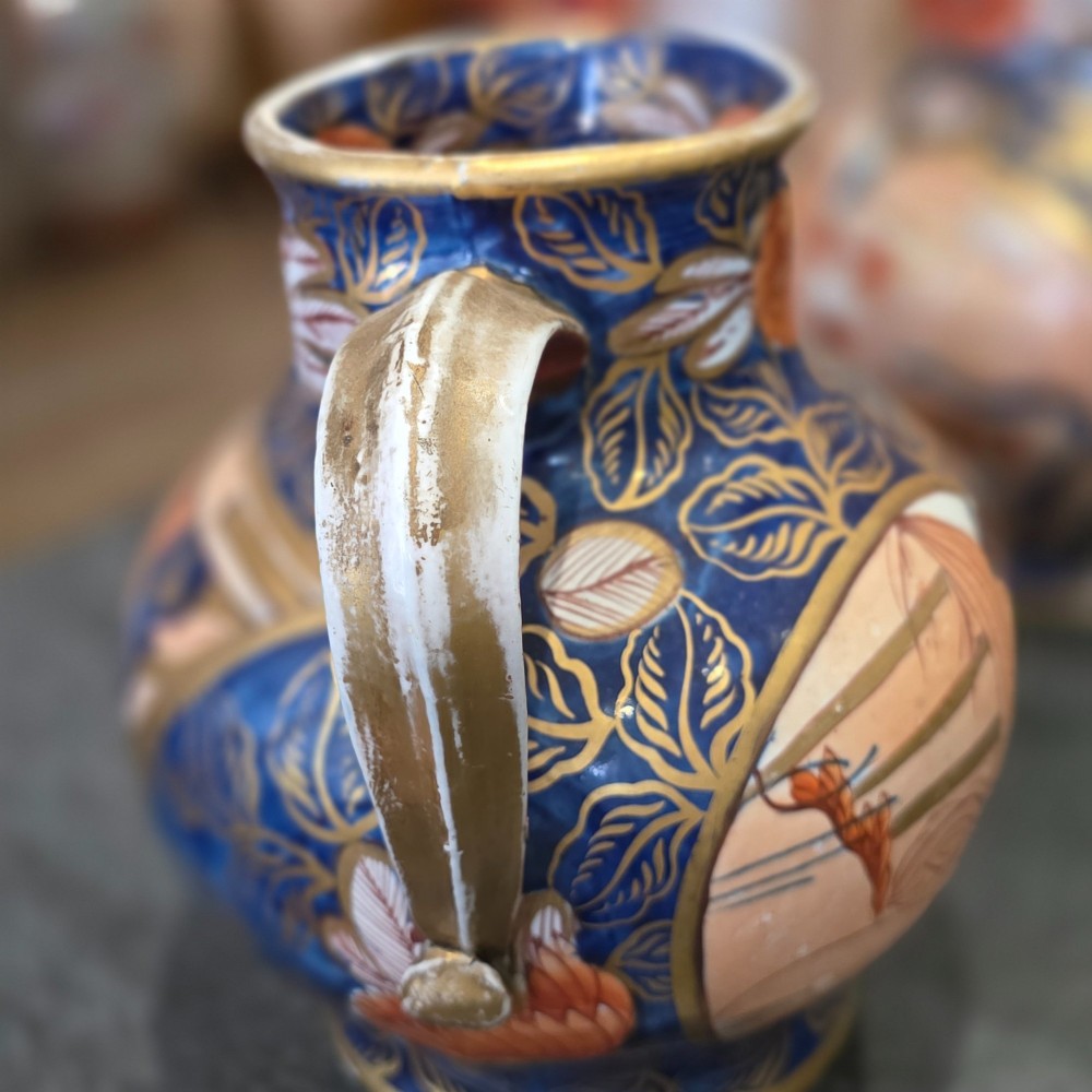 A pair of bulbous stoneware jugs decorated in cobalt blue, terracotta, and gold Imari style patterns with raised handles. View VI