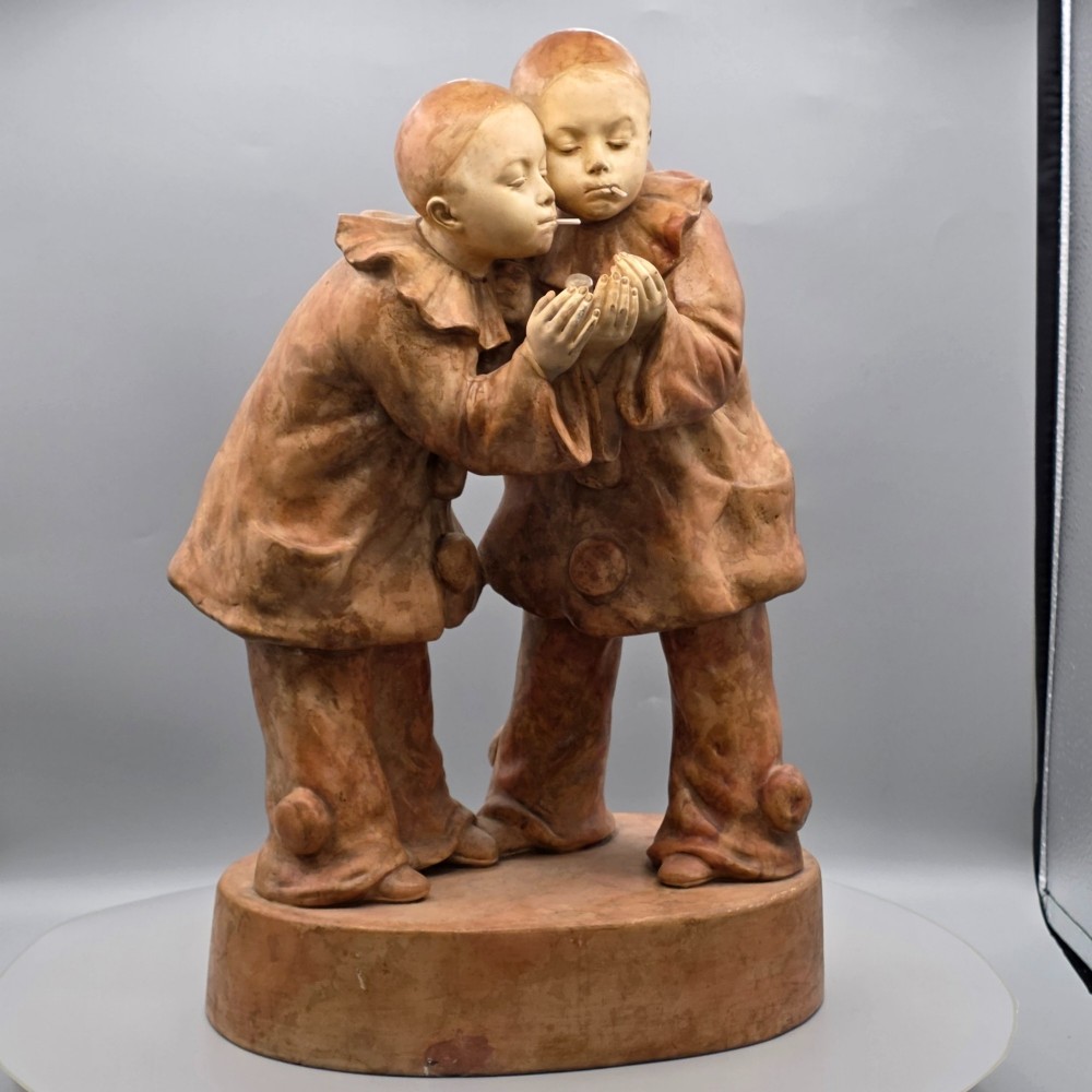 A terracotta sculpture featuring two Pierrot figures in ruffled collars standing together on an oval plinth, designed as a lamp base.