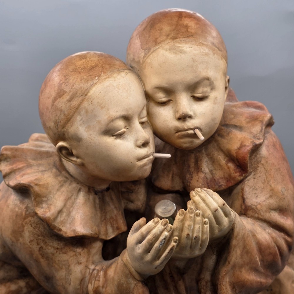A terracotta sculpture featuring two Pierrot figures in ruffled collars standing together on an oval plinth, designed as a lamp base. View V
