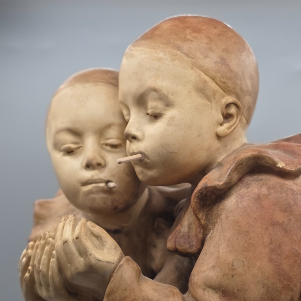 A terracotta sculpture featuring two Pierrot figures in ruffled collars standing together on an oval plinth, designed as a lamp base. View VI