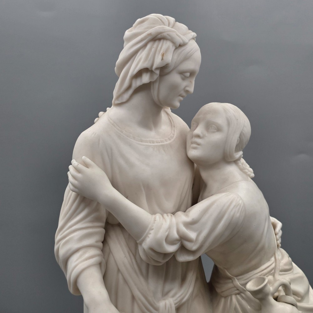 A Victorian off-white parian porcelain figural group depicting three women in classical draped robes on an oval base. View II