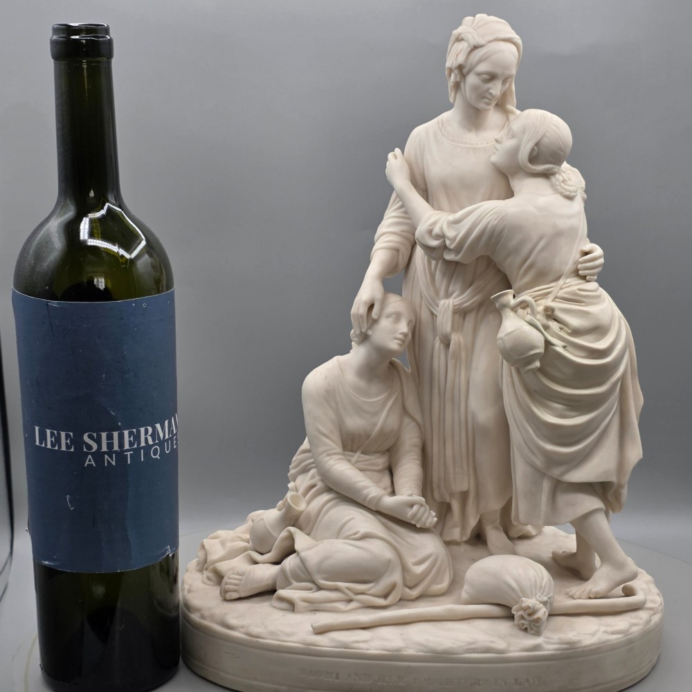 A Victorian off-white parian porcelain figural group depicting three women in classical draped robes on an oval base. View XV
