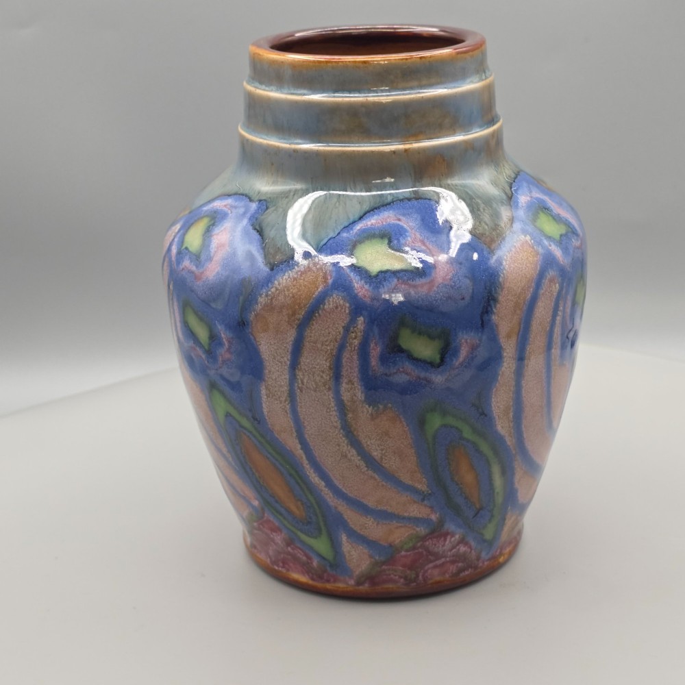 An Art Nouveau baluster-shaped stoneware vase with a stepped rim, featuring vibrant blue, pink, green, and ochre glazes forming abstract floral motifs. View II
