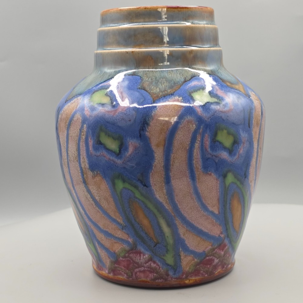 An Art Nouveau baluster-shaped stoneware vase with a stepped rim, featuring vibrant blue, pink, green, and ochre glazes forming abstract floral motifs. View III