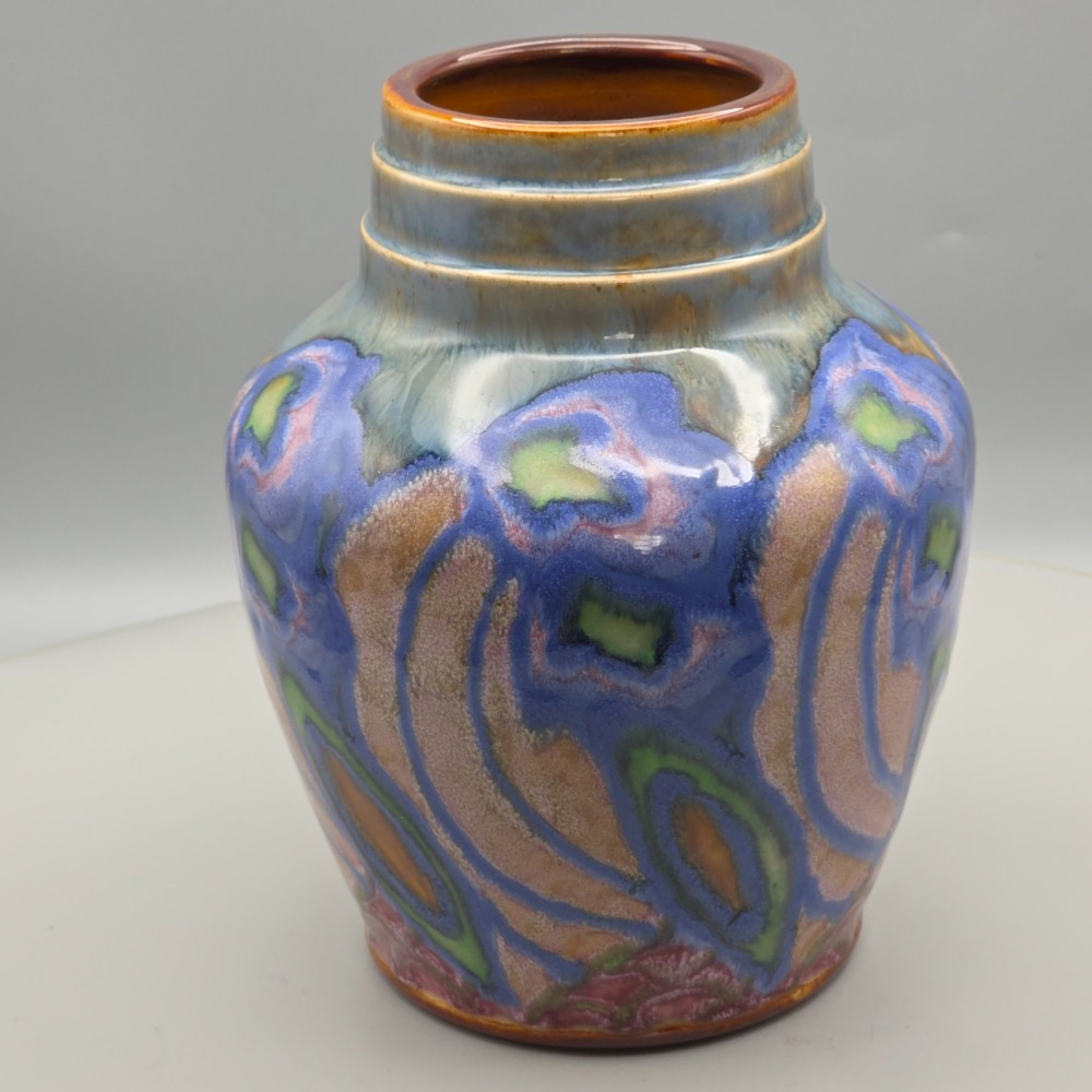 An Art Nouveau baluster-shaped stoneware vase with a stepped rim, featuring vibrant blue, pink, green, and ochre glazes forming abstract floral motifs. View VI
