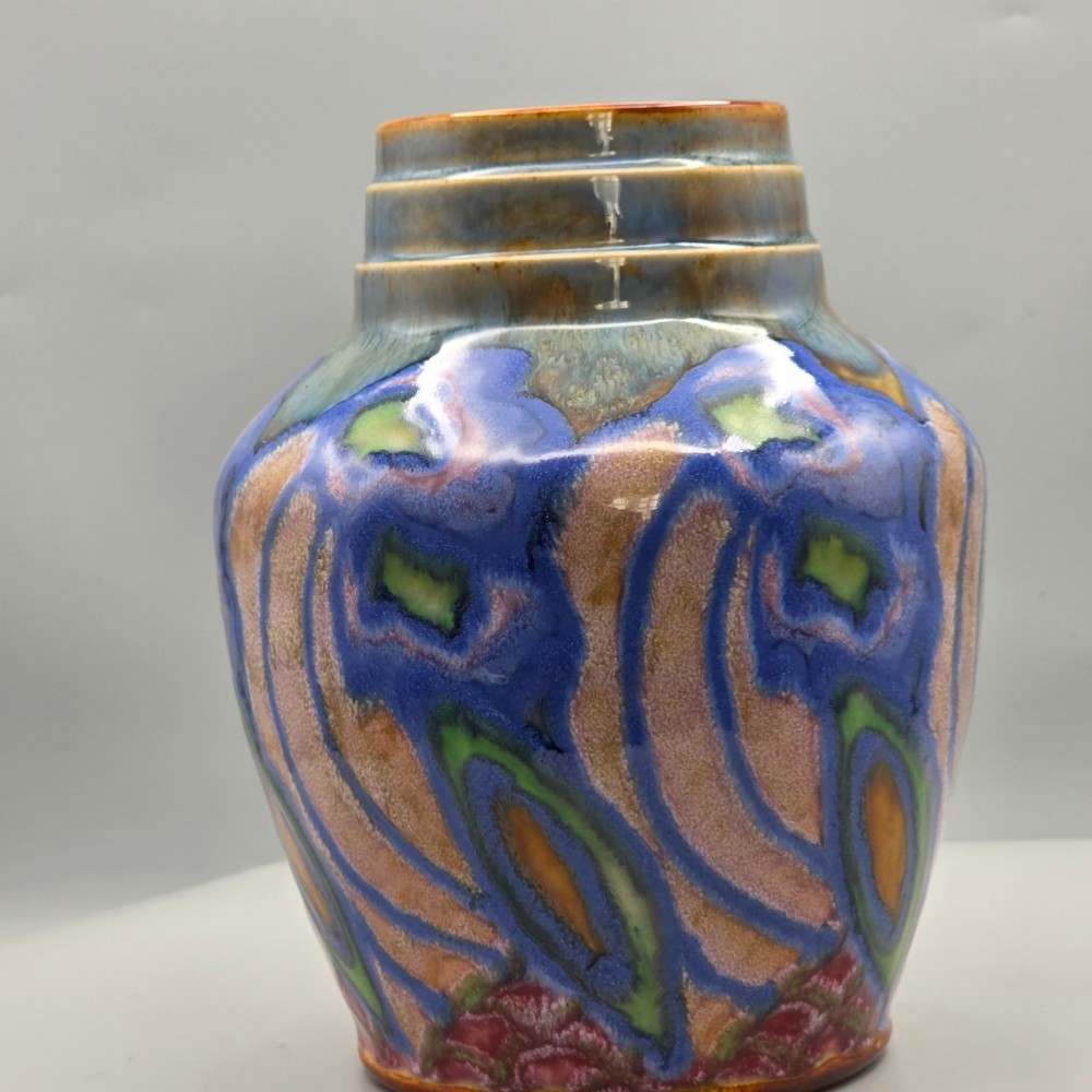 An Art Nouveau baluster-shaped stoneware vase with a stepped rim, featuring vibrant blue, pink, green, and ochre glazes forming abstract floral motifs. View VII