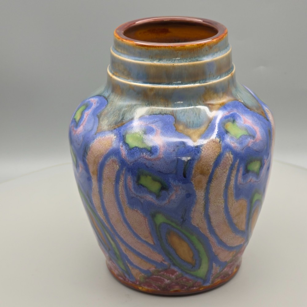 An Art Nouveau baluster-shaped stoneware vase with a stepped rim, featuring vibrant blue, pink, green, and ochre glazes forming abstract floral motifs. View IX
