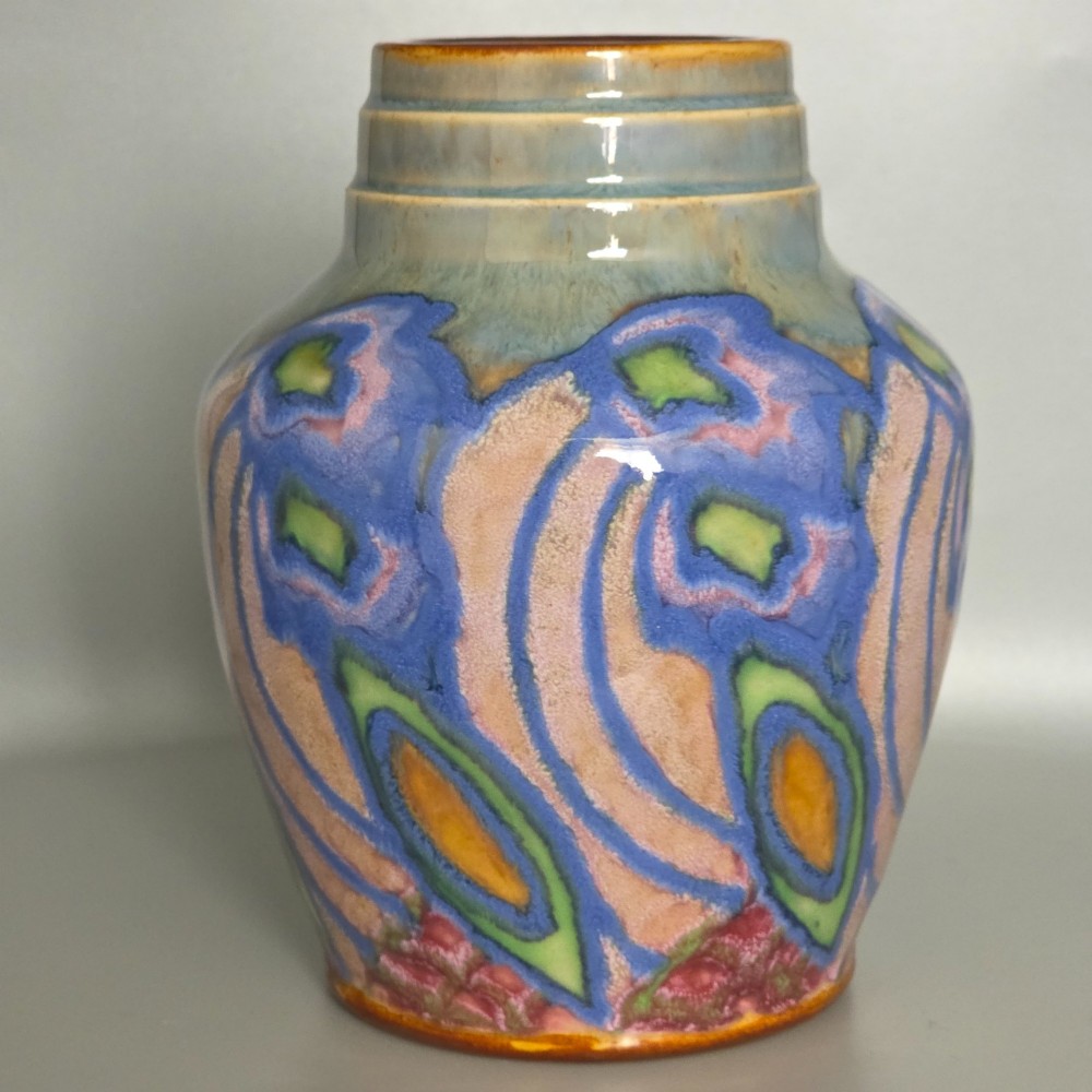 An Art Nouveau baluster-shaped stoneware vase with a stepped rim, featuring vibrant blue, pink, green, and ochre glazes forming abstract floral motifs. View X