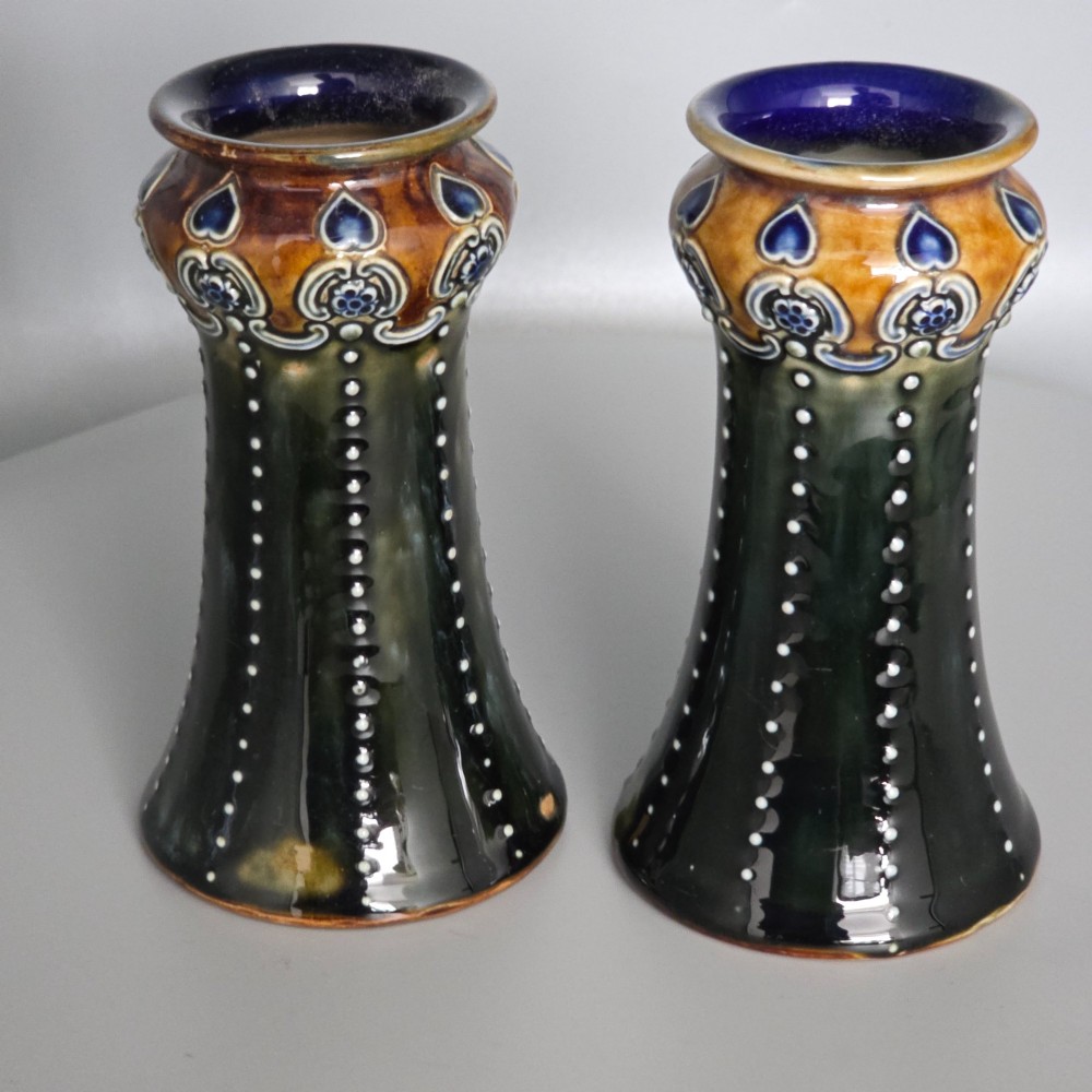 A pair of 1920s Royal Doulton Art Nouveau stoneware vases featuring flared bases, mottled dark green and brown glazes, and beaded shoulder decorations with blue accents. View II