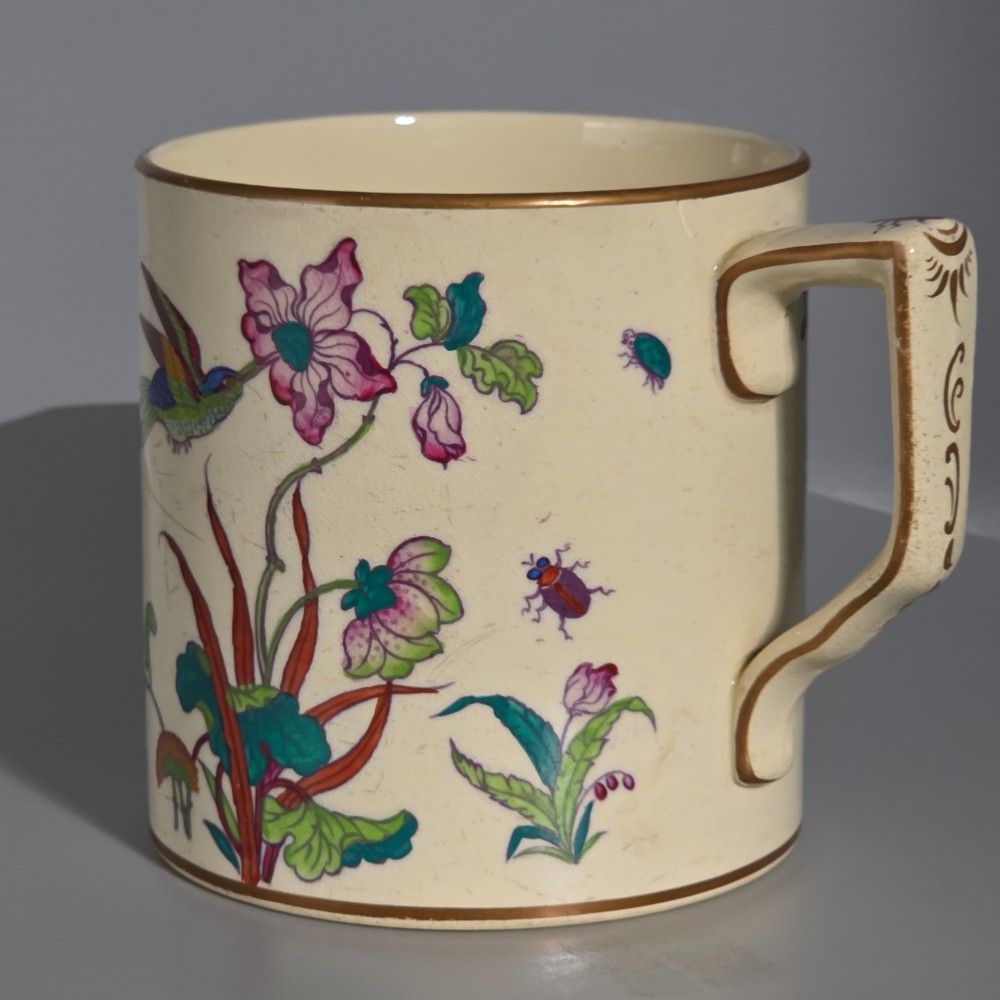 A large cream porcelain mug decorated with hand-painted polychrome birds, insects, flowers, and a gilded rim. View V