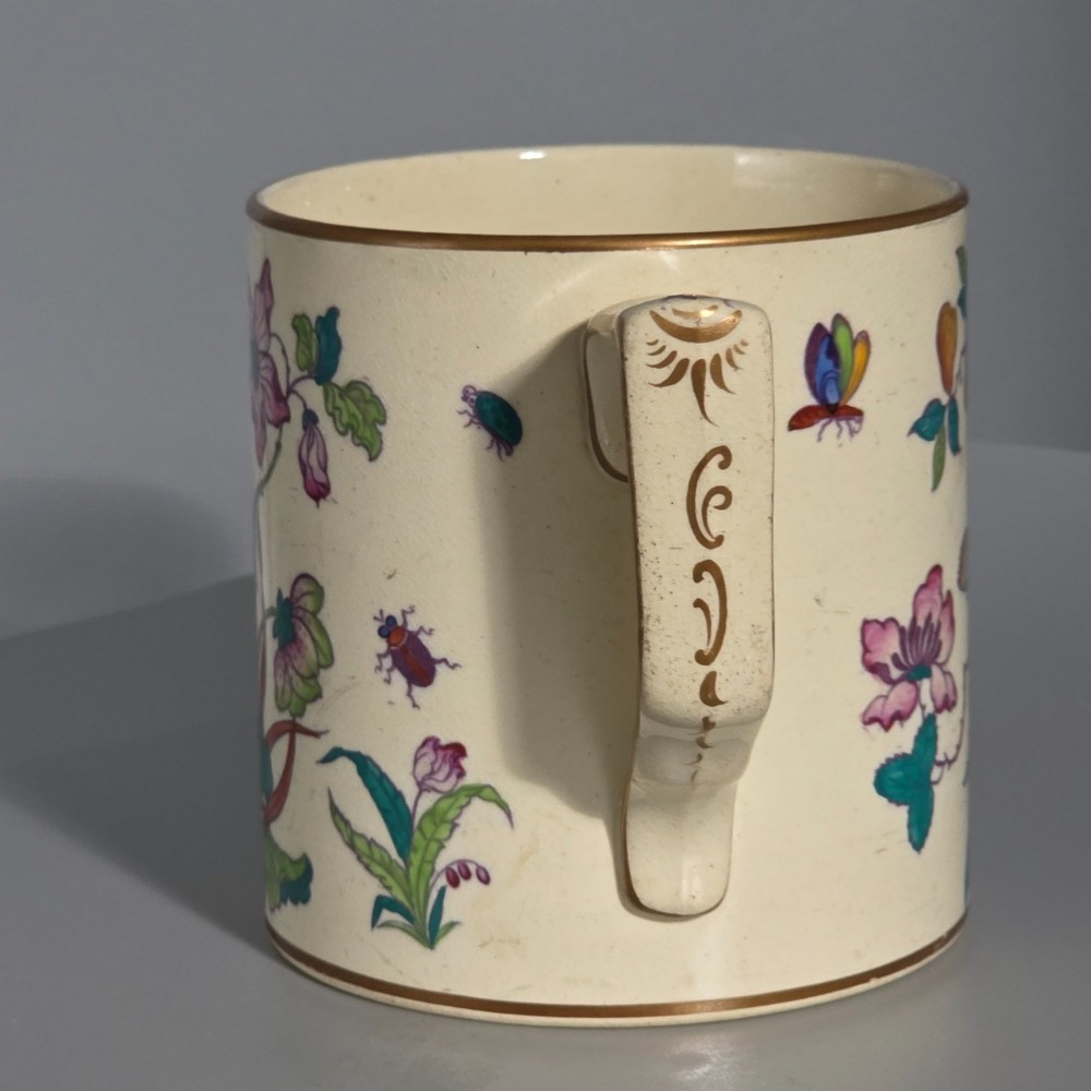 A large cream porcelain mug decorated with hand-painted polychrome birds, insects, flowers, and a gilded rim. View VI