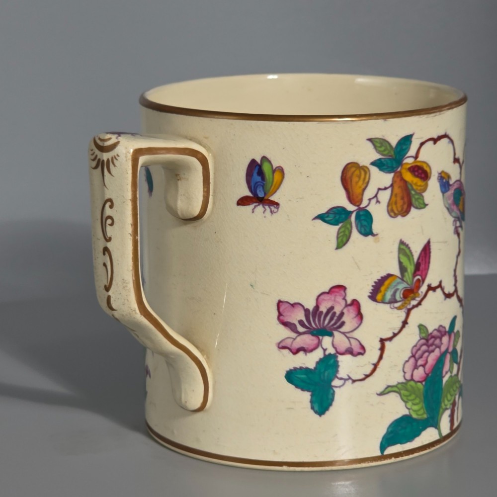 A large cream porcelain mug decorated with hand-painted polychrome birds, insects, flowers, and a gilded rim. View IX